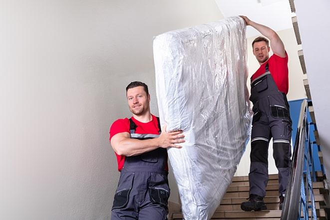 heavy lifting workers transporting a box spring out of a building in Burlington, WI